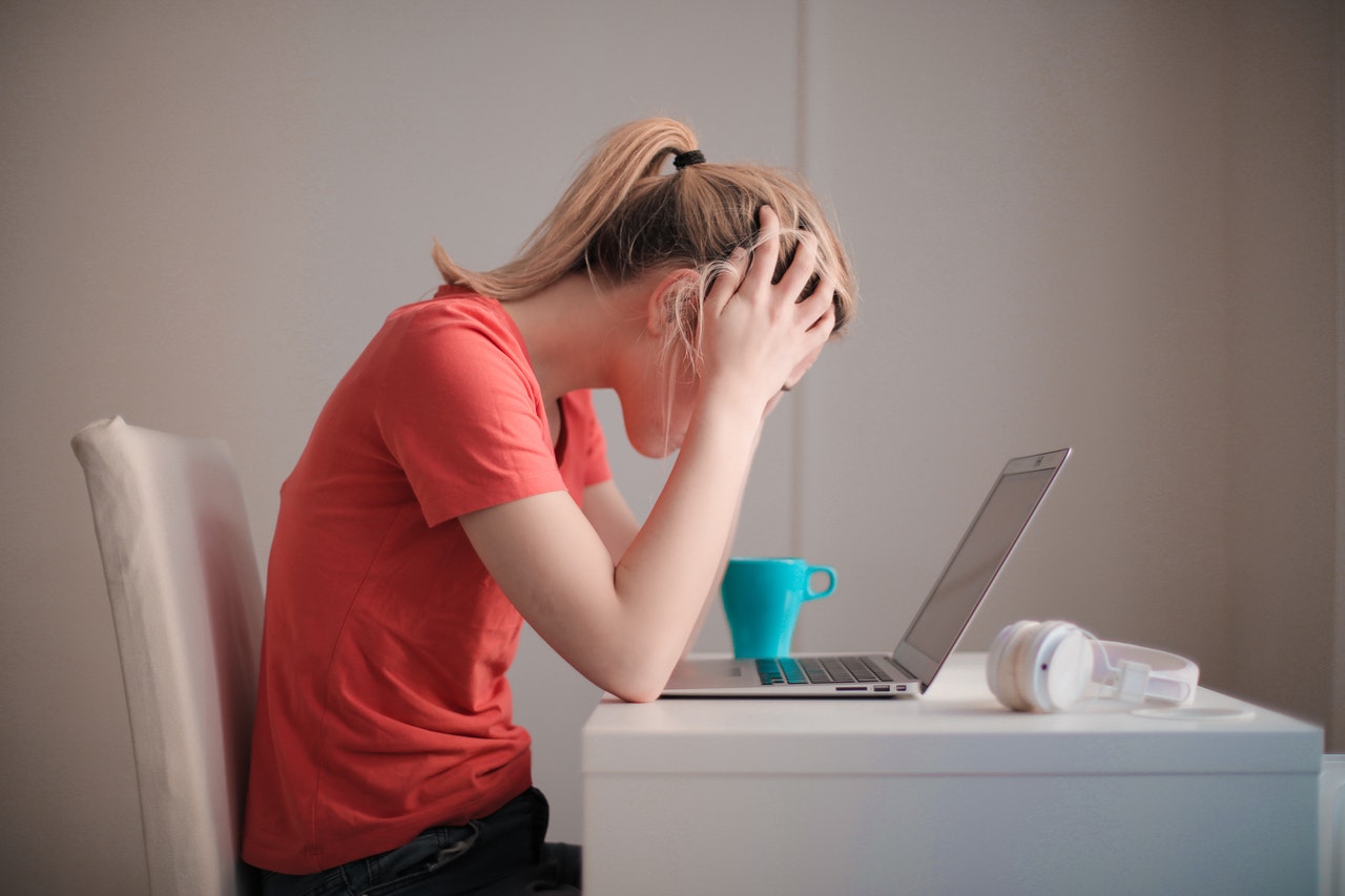 A woman sitting at her desk with her head in her hands.